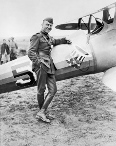 Eddie Rickenbacker, dressed in uniform, stands next to his World War I plane in a field near Toul, France. 